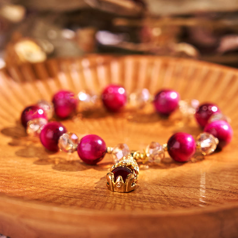 Red Tiger Eye PiXiu Bracelet – Deep red beads with gold PiXiu charm on wooden plate, protection jewelry