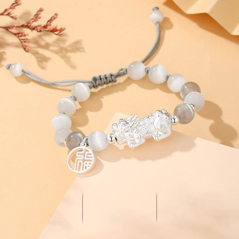Black Obsidian Pi Xiu Bracelet – White cat eye bead variant flat lay, silver Pi Xiu, fortune charm pendant, gray cord