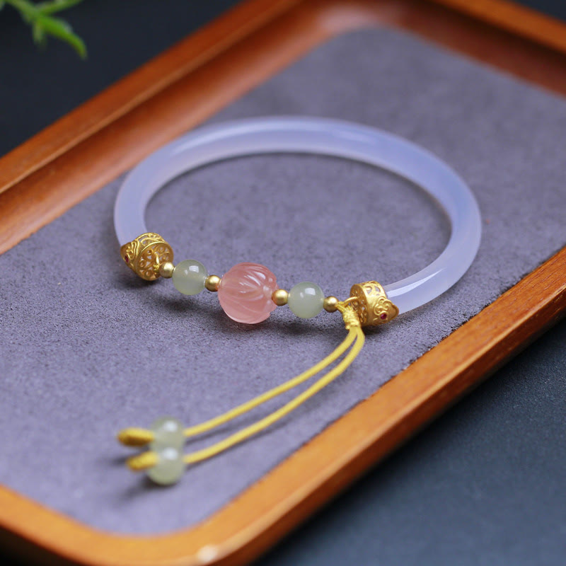 White Agate Lotus Hetian Jade Bracelet – translucent bangle with pink lotus bead on wood tray, mindful