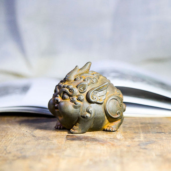 Handmade PiXiu Iron Powder Rust Cast Resin Wealth Statue – Side profile of rusted PiXiu with wing details, book background