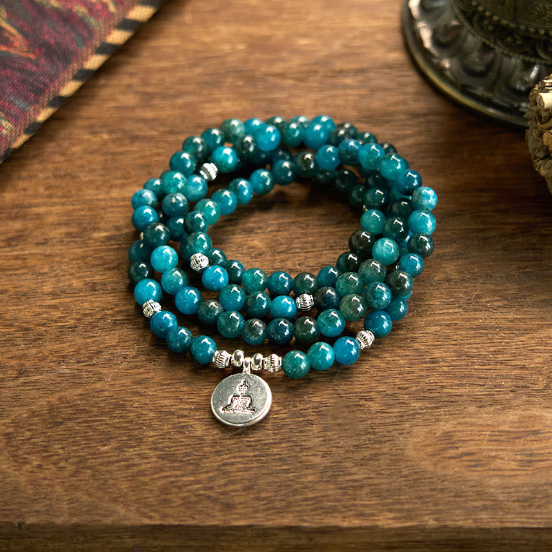 108 Mala Apatite Bracelet - coiled teal beads with Buddha meditation charm on wooden table, mindfulness