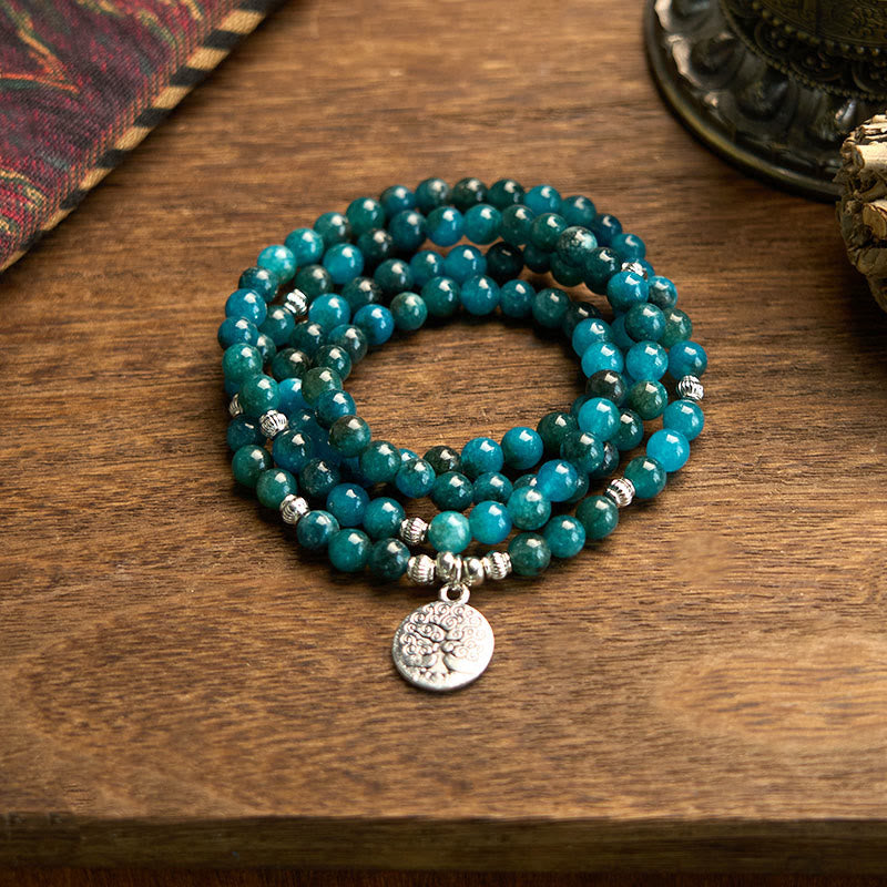 108 Mala Apatite Bracelet - coiled teal beads with Tree of Life charm on wooden table, yoga jewelry
