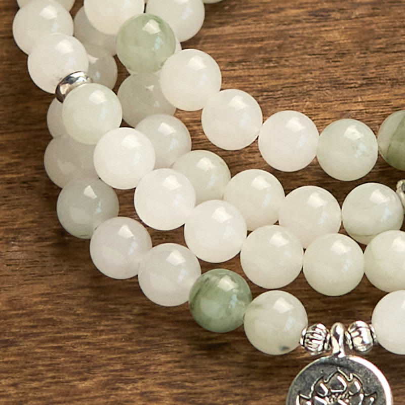 108 Mala Tianshan Jade Lotus Bracelet - macro close-up on wood grain, lotus medallion, artisanal texture