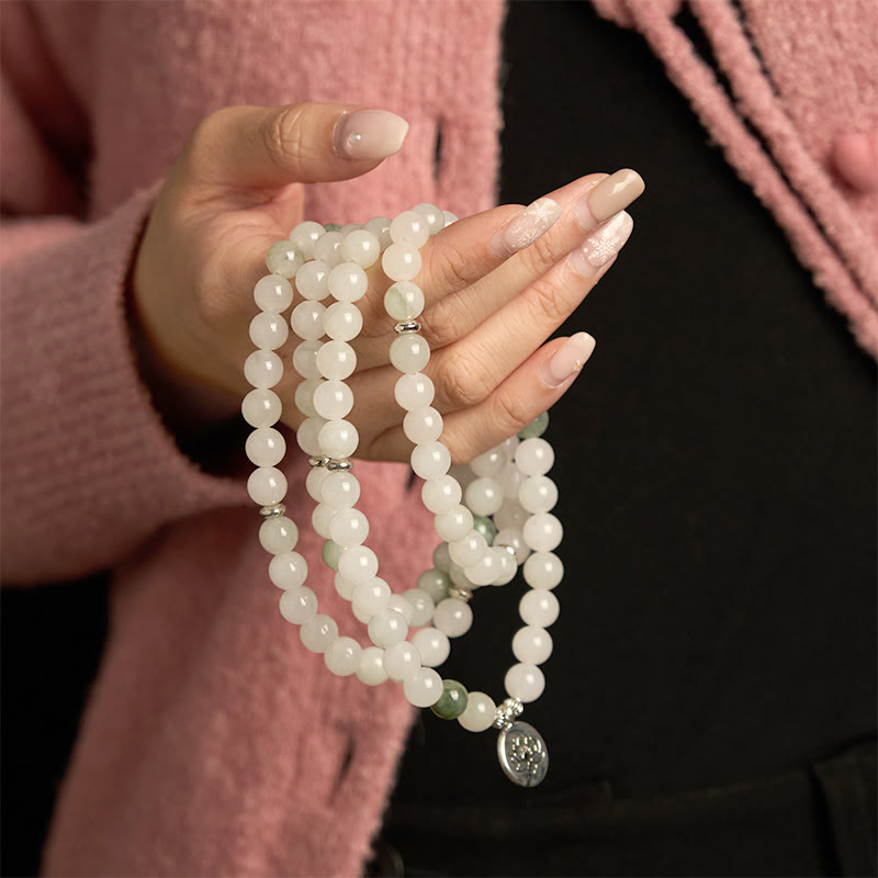 108 Mala Tianshan Jade Lotus Bracelet - draped over hand with pink cardigan, silver lotus detail, calming