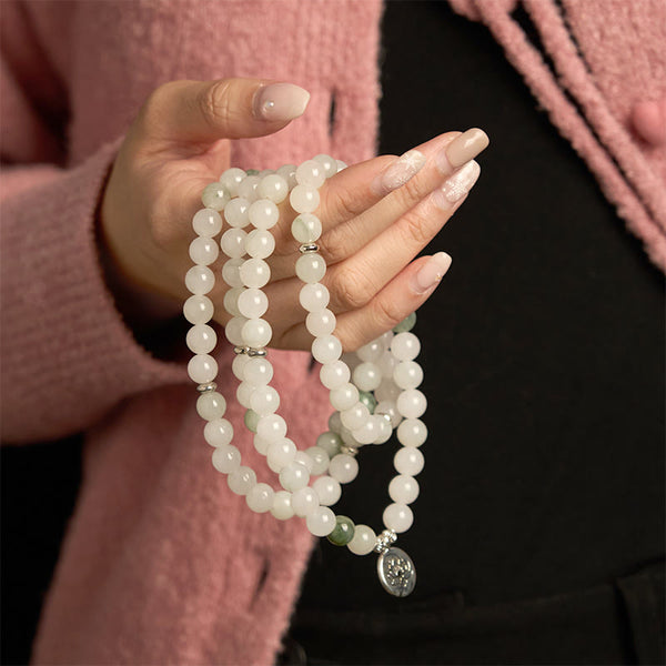 108 Mala Tianshan Jade Lotus Bracelet - draped over hand with pink cardigan, silver lotus detail, calming