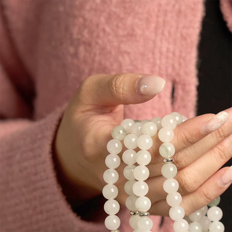 108 Mala Tianshan Jade Lotus Bracelet - cupped hand with floral nail art, pink knit backdrop, feminine grace