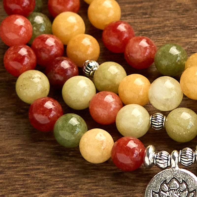 108 Mala Topaz Jasper Lotus Bracelet - macro close-up of red green amber beads on dark wood, grounding