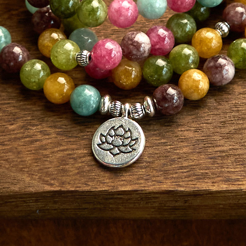 108 Mala Tourmaline Lotus Wisdom Bracelet - silver lotus charm close-up on wood grain, Healing