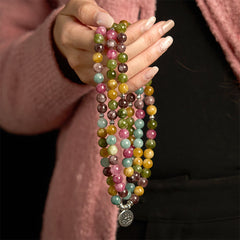 108 Mala Tourmaline Lotus Wisdom Bracelet - held in hand, multicolor gemstone strands, black backdrop, Protection