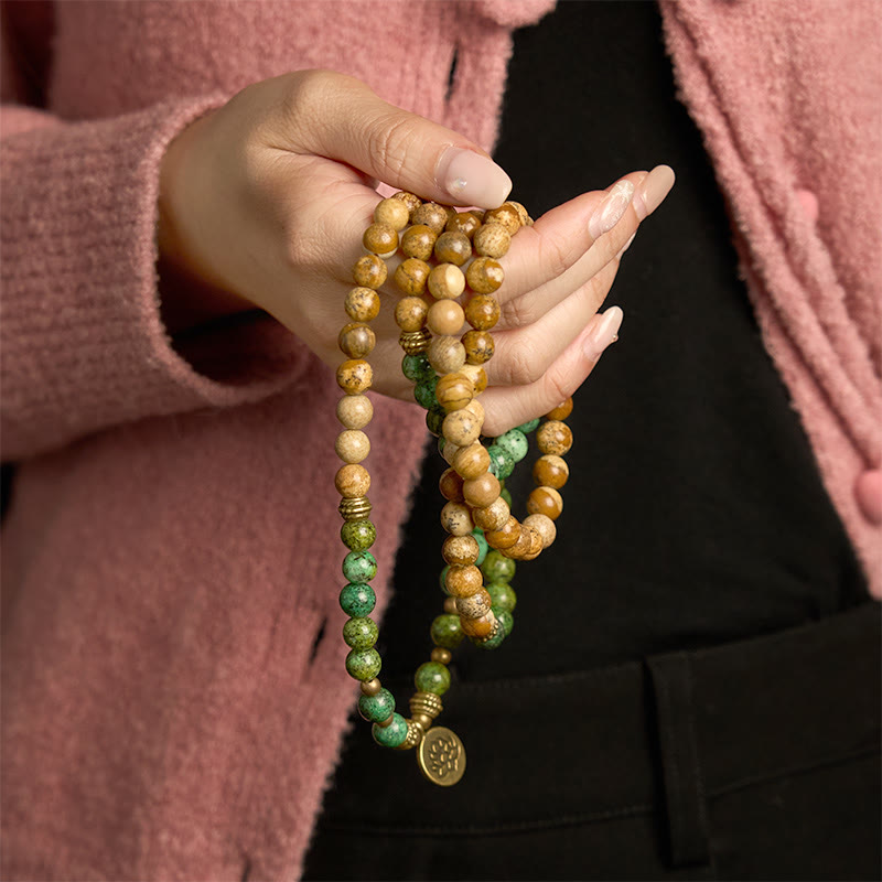 108 Mala Picture Jasper Turquoise Lotus Bracelet - held in hand, brown and green stones, pink sweater, Stability