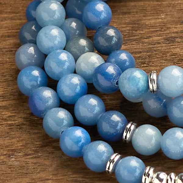108 Mala Blue Aventurine Lotus Calm Bracelet – coiled blue gemstone beads with silver spacers on rustic wood, Focus
