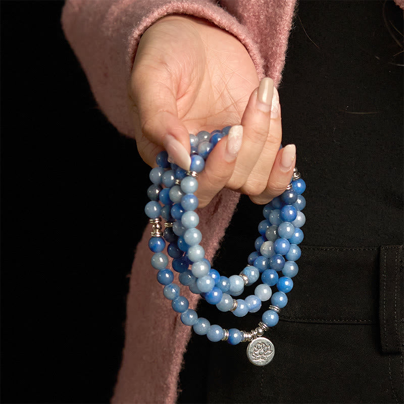 108 Mala Blue Aventurine Lotus Calm Bracelet – blue ombre beads with silver lotus charm draped in fingers, Focus
