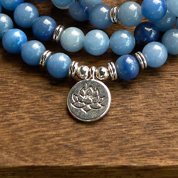 108 Mala Blue Aventurine Lotus Calm Bracelet – blue ombre bracelet with silver lotus charm on wood grain close-up, Calm