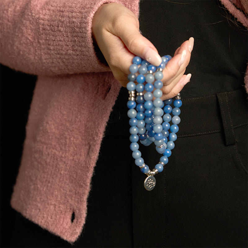 108 Mala Blue Aventurine Lotus Calm Bracelet – blue beaded strands with silver lotus charm held over pink sweater, Calm