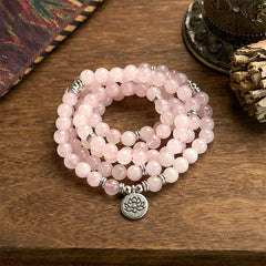 Rose Quartz Lotus Mala Bracelet - pink beads coiled on wood, serene