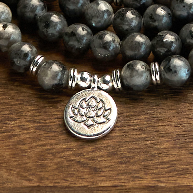 108 Mala Black Glitter Stone Lotus Bracelet - diagonal strands on warm wood, silver lotus focus, striking resilience