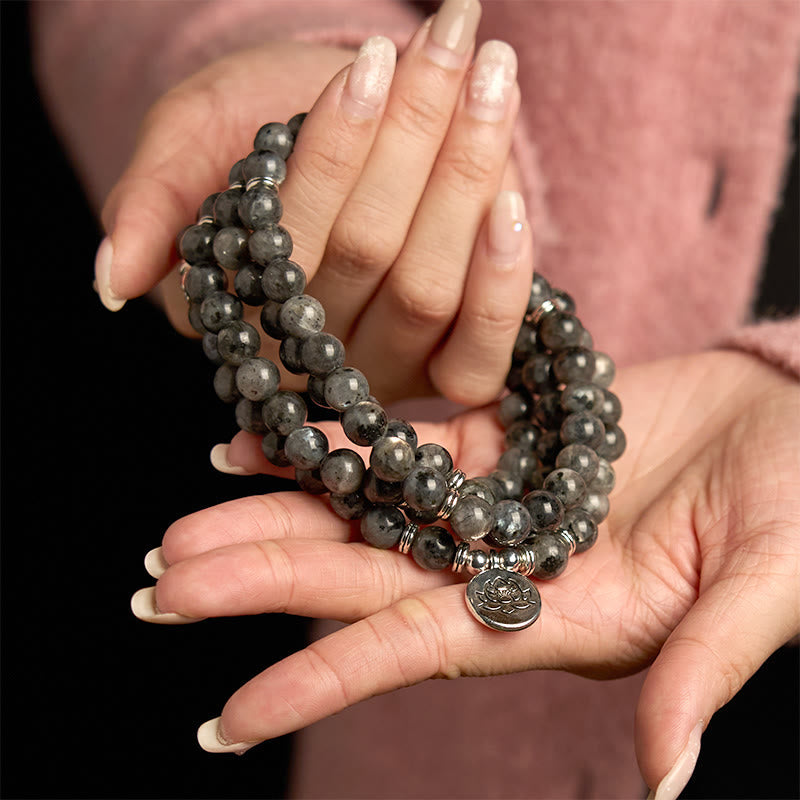 108 Mala Black Glitter Stone Lotus Bracelet - cradled in hands over pink sweater, silver lotus, bold positivity