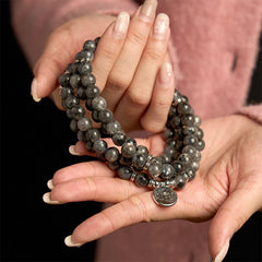108 Mala Black Glitter Stone Lotus Bracelet - cradled in hands over pink sweater, silver lotus, bold positivity