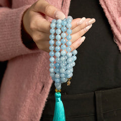 108 Mala Aquamarine Lotus Healing Bracelet – multi-strand aquamarine beads with turquoise tassel held in hand, Clarity