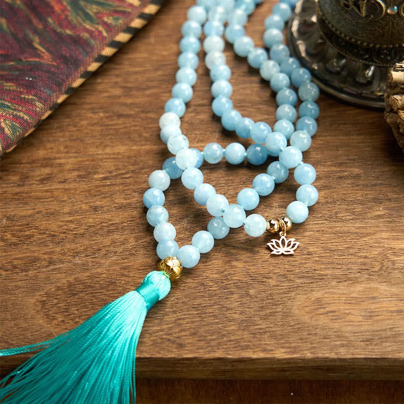 108 Mala Aquamarine Lotus Healing Bracelet – pale blue beads with gold lotus charm on clean wooden surface, Calm