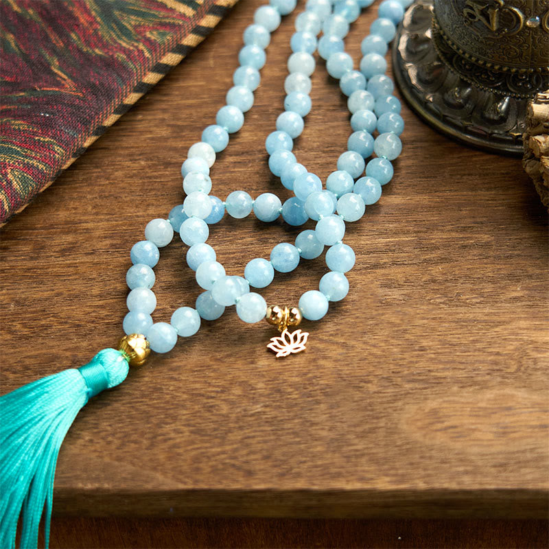 108 Mala Aquamarine Lotus Healing Bracelet – aquamarine beads with gold lotus pendant and silk tassel on wood, Peaceful