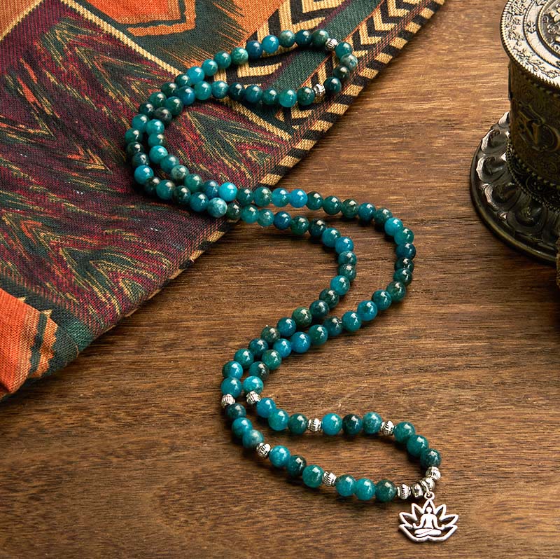 108 Mala Apatite Bracelet - mala in S-curve with lotus pendant beside singing bowl and ethnic textile