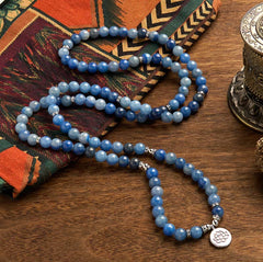 108 Mala Blue Aventurine Lotus Calm Bracelet – S-curve blue gradient beads with silver lotus pendant on textile, Peace