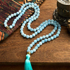 108 Mala Aquamarine Lotus Healing Bracelet – S-curve aquamarine beads with gold guru bead beside prayer wheel, Clarity