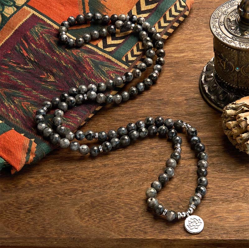 108 Mala Black Glitter Stone Lotus Bracelet - serpentine drape on brown wood, silver-blue flash, spiritual strength