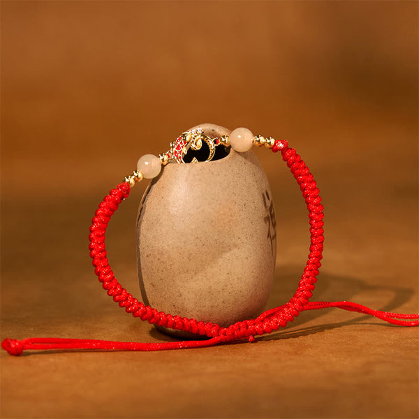 Silver Jade Cinnabar Koi Snake Bracelet – gold floral charm with jade beads on ceramic vessel, warm brown backdrop