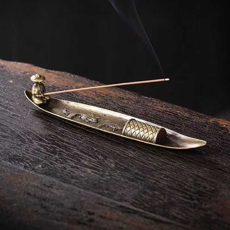 Koi Fish Boat Incense Burner - bronze fishing boat with fisherman, lit incense and smoke on dark wood