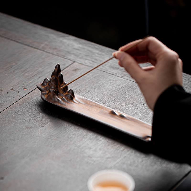 Mountains Boat Ceramic Incense Burner – hand placing incense into brown mountain ceramic holder, tea ceremony setup