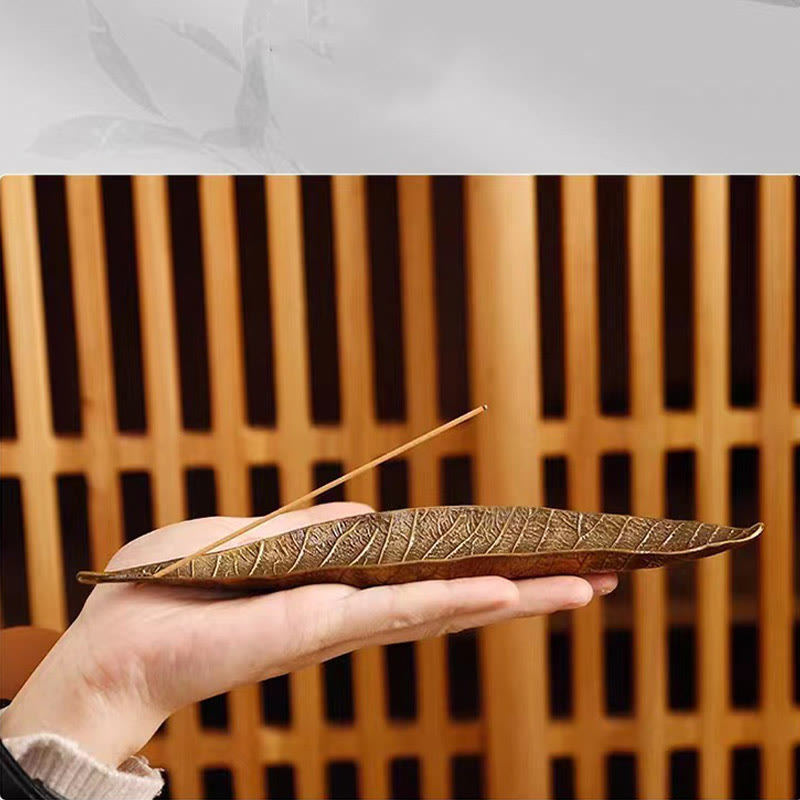 Oriental Leaf Alloy Incense Burner – hand holding reddish brown leaf holder against wooden lattice, delicate artisan craft