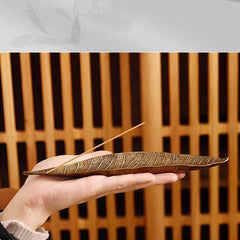 Oriental Leaf Alloy Incense Burner – hand holding reddish brown leaf holder against wooden lattice, delicate artisan craft