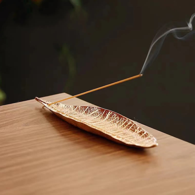 Oriental Leaf Alloy Incense Burner – gold leaf holder with smoking incense stick on wood surface, peaceful ambiance