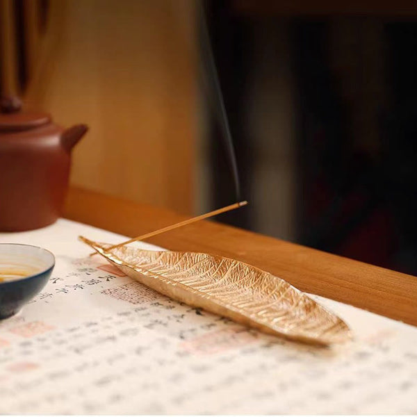 Oriental Leaf Alloy Incense Burner – gold leaf holder on tea table beside clay teapot and cup, serene tea ceremony