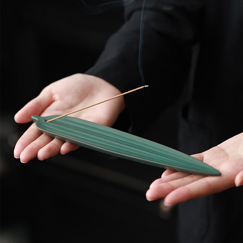 Green Bamboo Leaf Ceramic Incense Burner – hands holding dark green leaf burner with smoking incense, elegant presentation