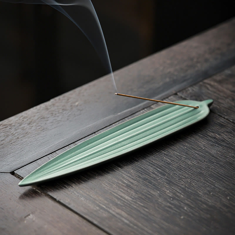 Green Bamboo Leaf Ceramic Incense Burner – light green leaf-shaped holder with incense smoke drifting on dark wood table