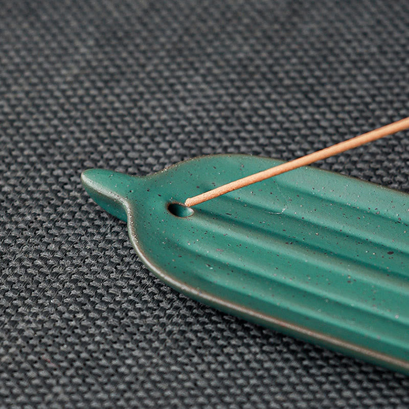 Green Bamboo Leaf Ceramic Incense Burner – macro of dark green leaf tip with incense stick in hole on woven mat