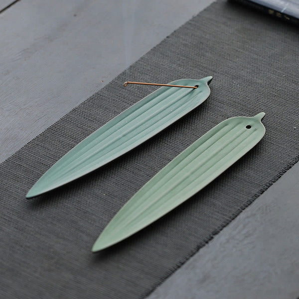 Green Bamboo Leaf Ceramic Incense Burner – two light green leaf holders side by side on grey tea mat, one with incense stick