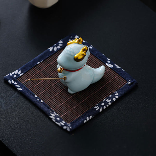 Ceramic Dragon Bell Incense Burner – low side view holding incense with smoke, bamboo mat base, Ritual