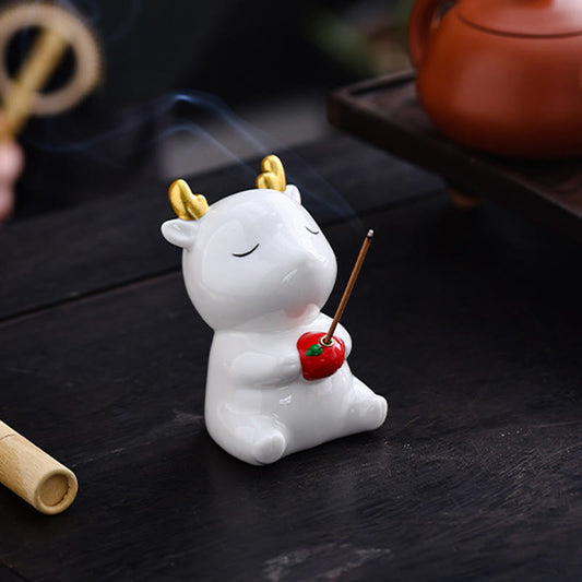 Deer Ceramic Incense Burner – White deer with gold antlers on dark wood, smoke curling from red apple, incense holder