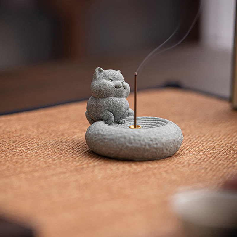 Lazy Cat Sandstone Incense Burner – cat on woven fabric with incense smoke, tan textile background, mindfulness decor piece