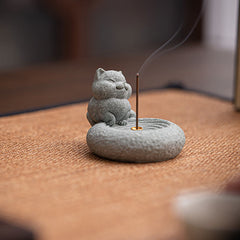 Lazy Cat Sandstone Incense Burner – cat on woven fabric with incense smoke, tan textile background, mindfulness decor piece
