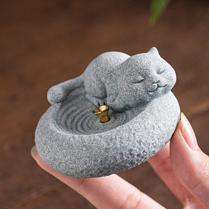 Lazy Cat Sandstone Incense Burner – cat held in hand on blurred wood, greenery in background, lifestyle product photo