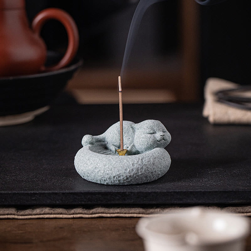 Lazy Cat Sandstone Incense Burner – sleeping cat on wood surface with smoke, greenery in background, cozy zen aesthetic