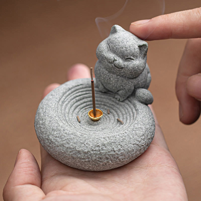 Lazy Cat Sandstone Incense Burner – cat held in open hand with burning incense, solid brown background, scale demonstration
