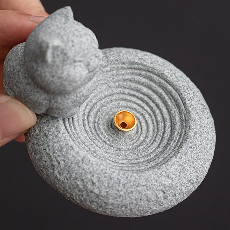 Lazy Cat Sandstone Incense Burner – sleeping cat on dark background held in hand, gold brass insert, palm-sized zen decor