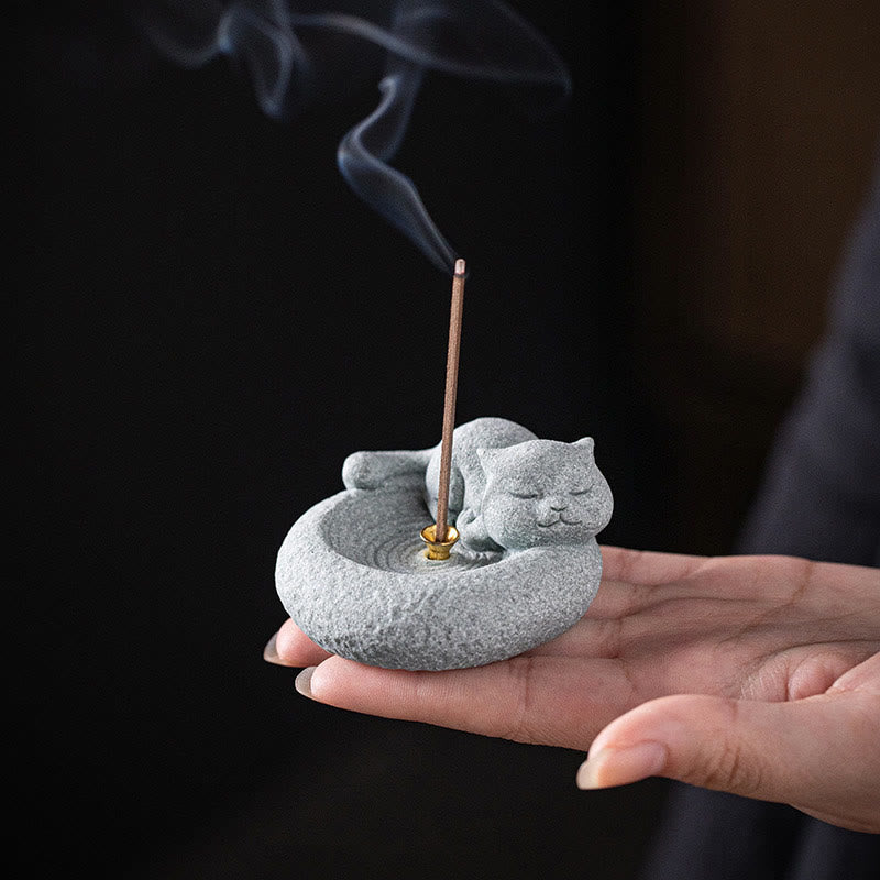 Lazy Cat Sandstone Incense Burner – sleeping cat with incense in hand, black background, smoke rising, palm-sized zen decor