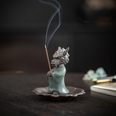 Ceramic Dragon King Incense Burner – dragon scholar holding lit incense with rising smoke, dark studio, Serenity